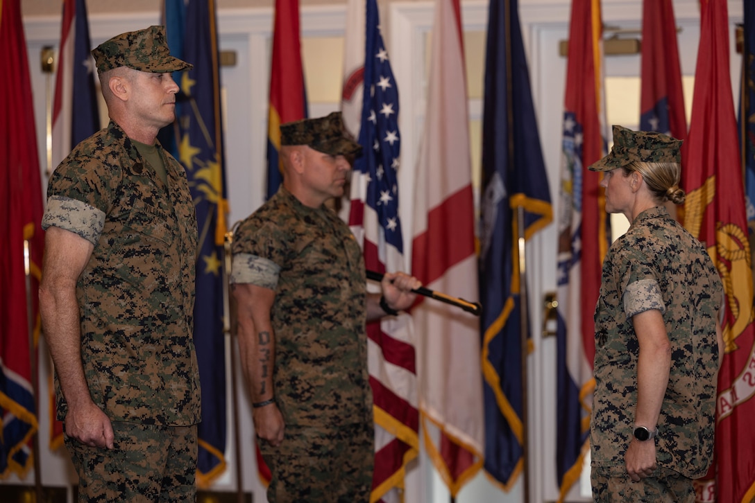 U.S. Marine Corps Sgt. Maj. Liam D. Williamson, incoming sergeant major of Marine Corps Base Quantico, left, Sgt. Maj. Michael R. Brown, outgoing sergeant major of MCB Quantico, and Col. Jenny A. Colegate, commanding officer of MCB Quantico, stand at attention during a relief and appointment ceremony at The Clubs at Quantico on MCB Quantico, Virginia, July 8, 2025. During the ceremony Brown was relieved of his duties as sergeant major of MCB Quantico by Williams. (U.S. Marine Corps photo by Lance Cpl. David Brandes)