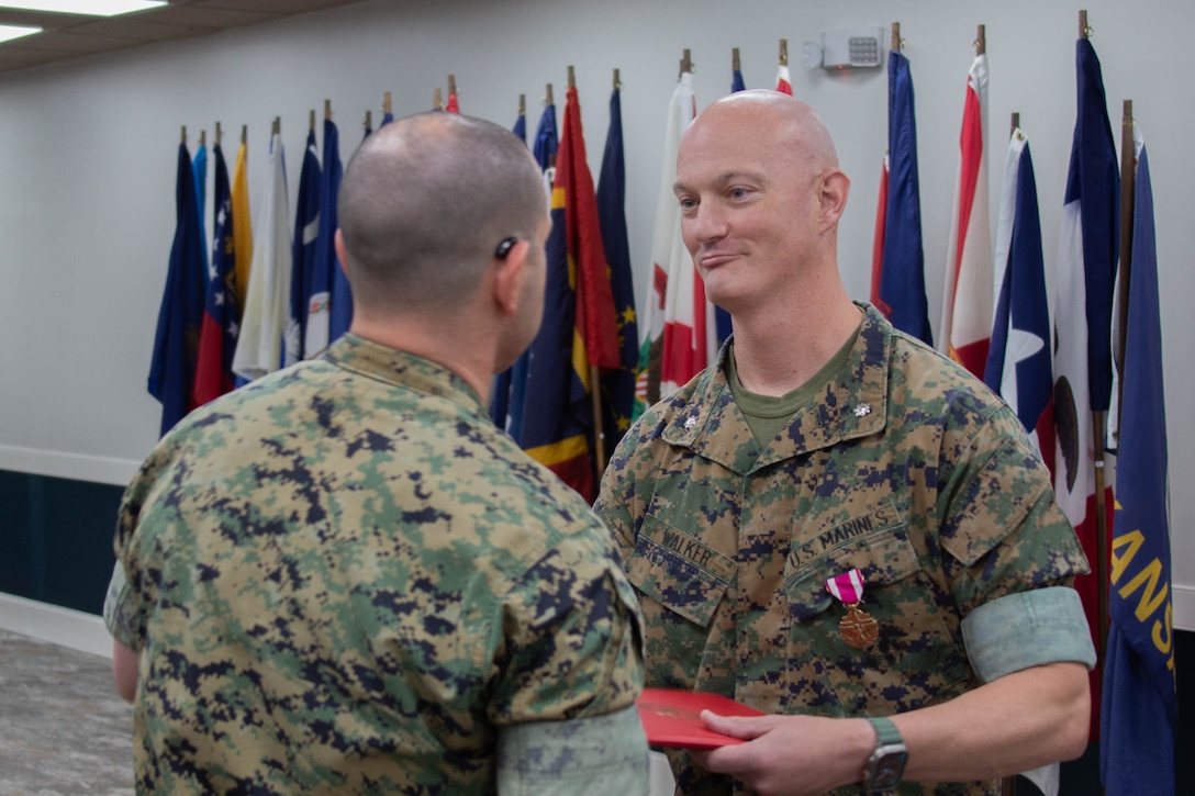U.S. Marine Corps Col. Bryan Eovito, left, commanding officer, Marine Corps Cyberspace Operations Group, presents Lt. Col. Andrew Walker, outgoing commanding officer, 2nd Network Battalion, Marine Corps Cyberspace Operations Group, with a Meritorious Service Medal during the 2nd Network Battalion change of command ceremony at Tun Alley on Marine Corps Base Camp Lejeune, North Carolina, June 13, 2025. The change of command ceremony represents the passing of responsibility, authority and accountability from the outgoing commanding officer to the incoming commanding officer. (U.S. Marine Corps photo by Lance Cpl. Hunter Brock)