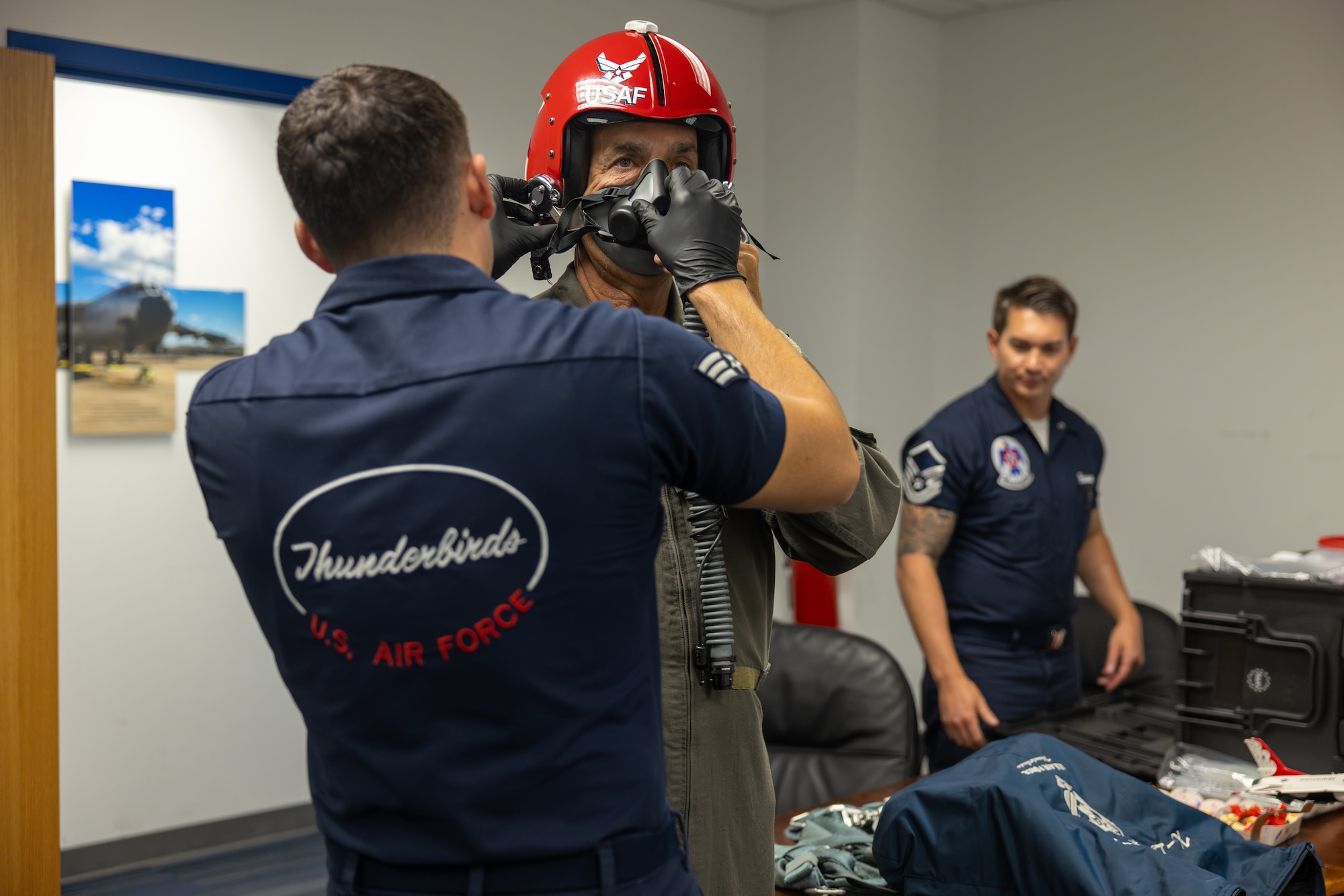Man being fitted by two others for a flight suit.