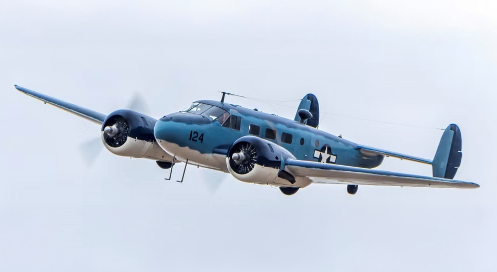 Blue aircraft with white underbelly flying in the sky