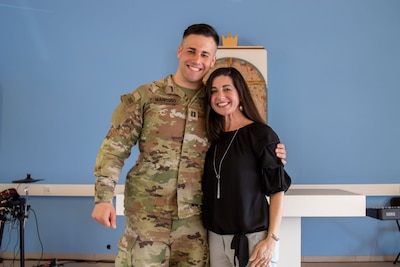 Service member smiles next to a woman in a black shirt