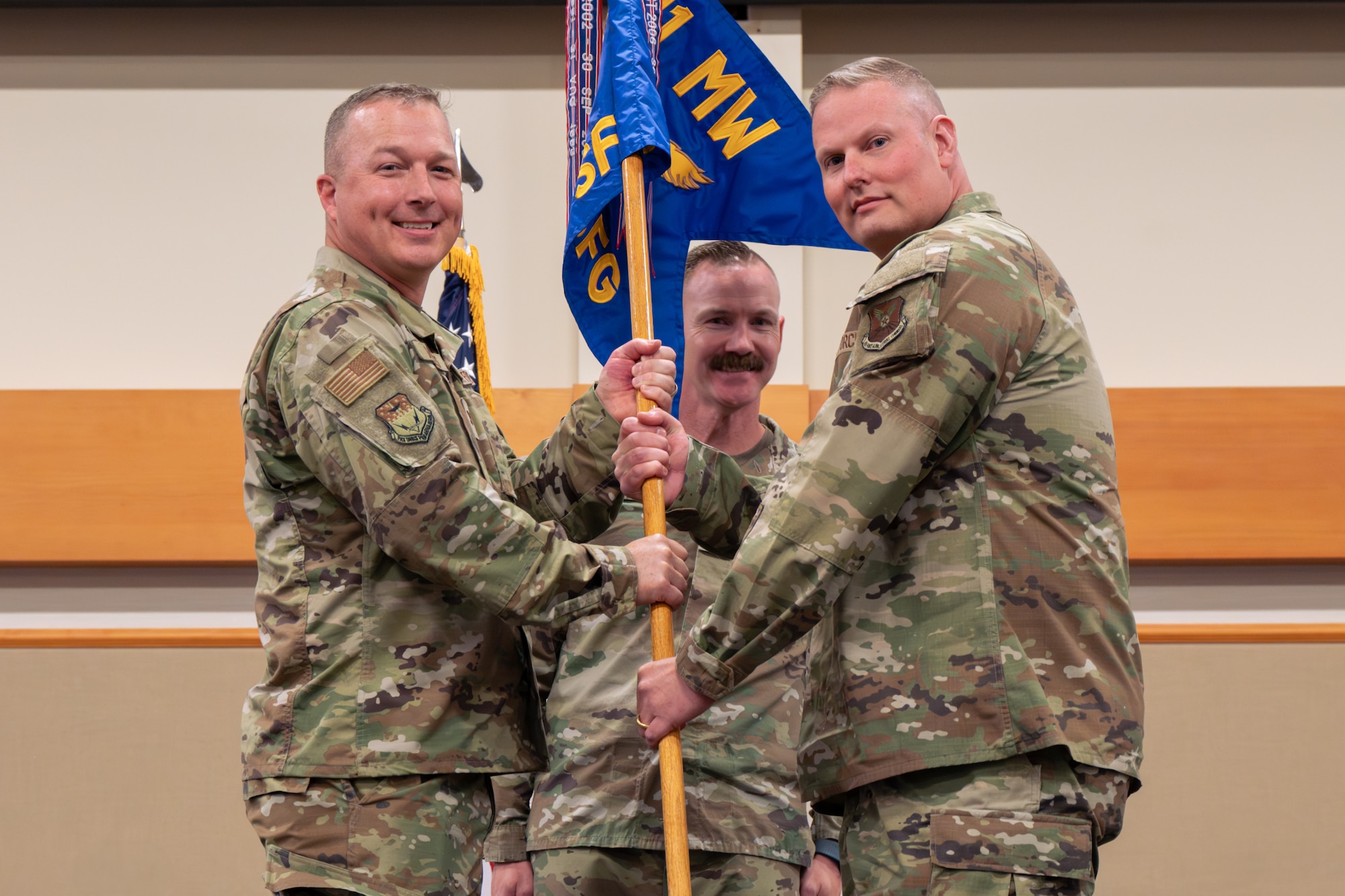 Men in uniform hold a flag.