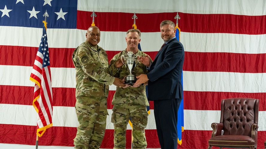Gen. Anthony Cotton, U.S. Strategic Command commander (left), U.S. Air Force Col. James Schlabach, 91st Missile Wing commander (center), and Mr. Randy Norwood, Omaha Chamber assistant vice president (right), pose for a photo during the Omaha Trophy ceremony at Minot Air Force Base, North Dakota, July 9, 2025. The Omaha Trophy was awarded to the 91MW due to their exemplary readiness, performance and dedication to safeguarding national security.