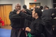 Army Reserve Lt. Col. Kenneth Roberts (left), an Area of Concentration, or AOC, 70H -- a Health Services Plans, Operations, Intelligence, Security and Training officer with the Joint Base McGuire-Dix-Lakehurst, N.J. based 7301st Medical Training Support Battalion, assists a student with hands-on martial arts training during a Jiu-Jitsu seminar in Clearwater, Fla., June 28, 2025. Roberts not only uses martial arts for self-defense and discipline, but he also participates in charity demonstration events that give back to the community. (U.S. Army photo by Sgt. Jerry T. Zuetrong)