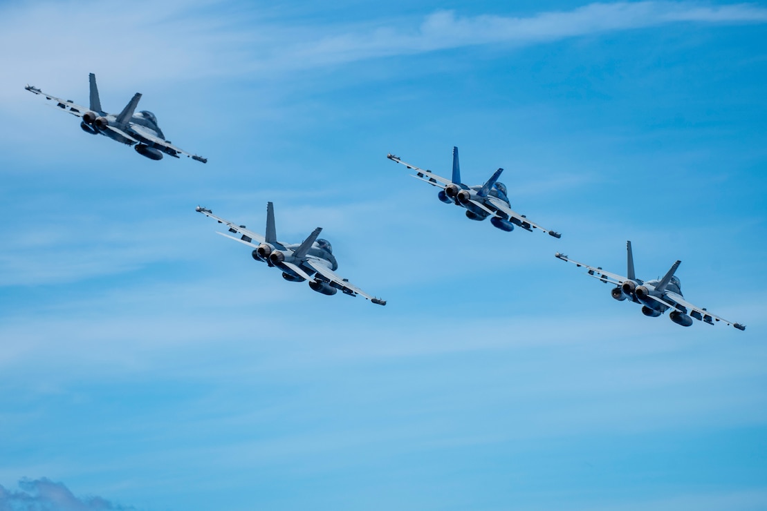 E/A-18G Growlers from the "Cougars" of Electronic Attack Squadron (VAQ) 139 fly in formation during an aerial change of command ceremony alongside the aircraft carrier USS Nimitz (CVN 68) in the South China Sea, May 27, 2025. Nimitz is underway in the U.S. 7th Fleet area of operations on a scheduled deployment, demonstrating the U.S. Navy's unwavering commitment to a free and open Indo-Pacific. (U.S. Navy photo by Mass Communication Specialist 2nd Class Carson Croom)