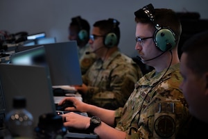 photo of US Airmen wearing headsets working on computers