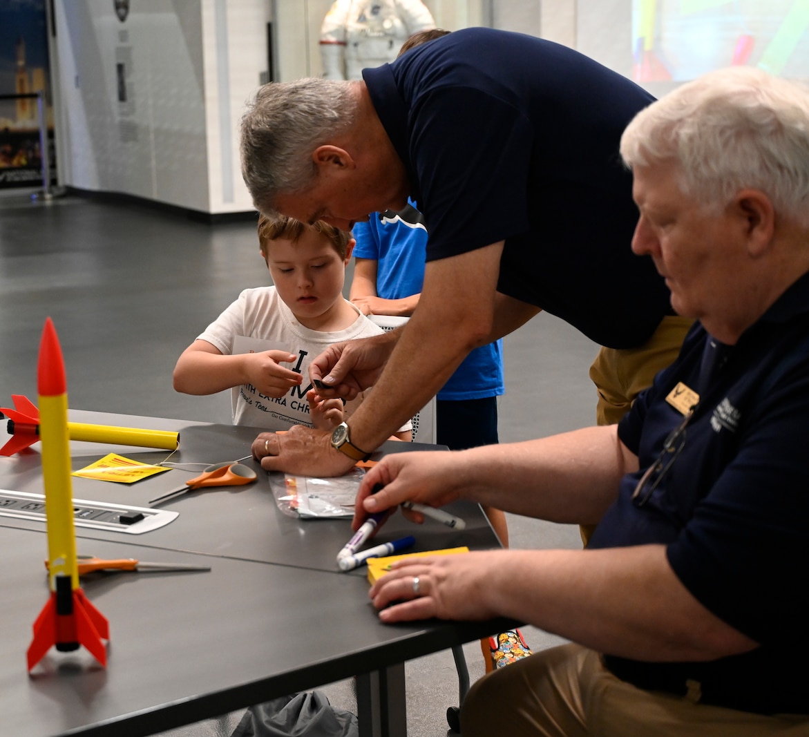 A student concentrates as he builds a model rocket with the guidance of a volunteer instructor. The activity takes place during the Modified Aerospace Camp at the National Museum of the U.S. Air Force.