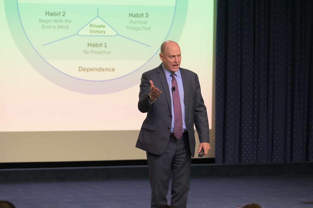 Man speaks on stage during event.