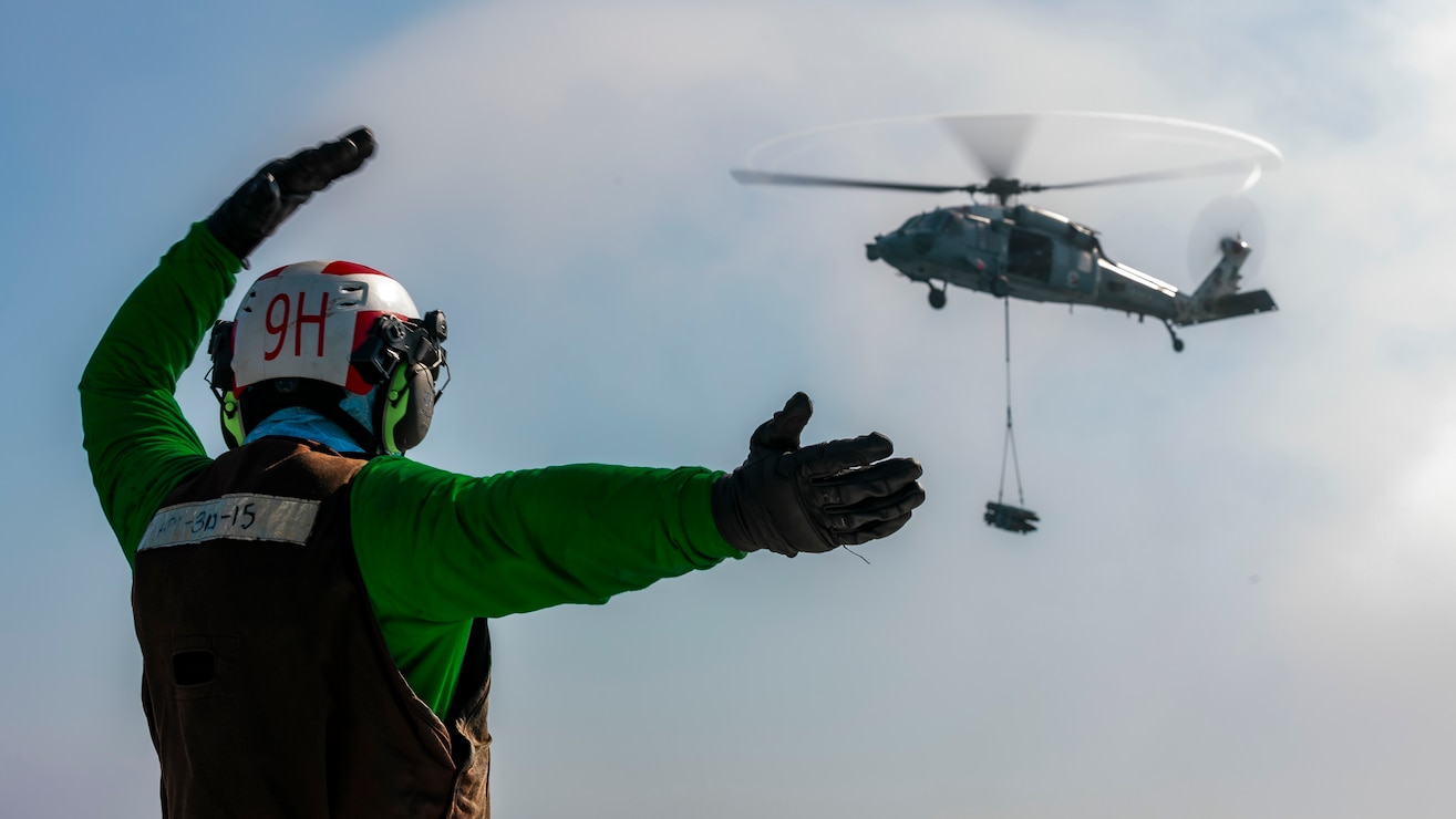 Airman Derek Jones, assigned to Helicopter Sea Combat Squadron (HSC) 9, signals a Carrier Air Wing 8 MH-60S Sea Hawk to the flight deck of the world's largest aircraft carrier, USS Gerald R. Ford (CVN 78), June 27, 2025. Gerald R. Ford, a first-in-class aircraft carrier and deployed flagship of Carrier Strike Group Twelve, incorporates modern technology, innovative shipbuilding designs, and best practices from legacy aircraft carriers to increase the U.S. Navy's capacity to underpin American security and economic prosperity, deter adversaries, and project power on a global scale through sustained operations at sea. (U.S. Navy photo by Mass Communication Specialist 2nd Class Tajh Payne)