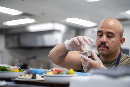 An Airman cleans the side of a condiment dish