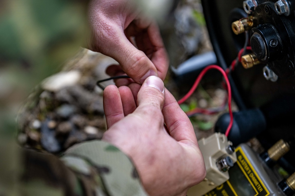 Hands working wiring on a training explosive device