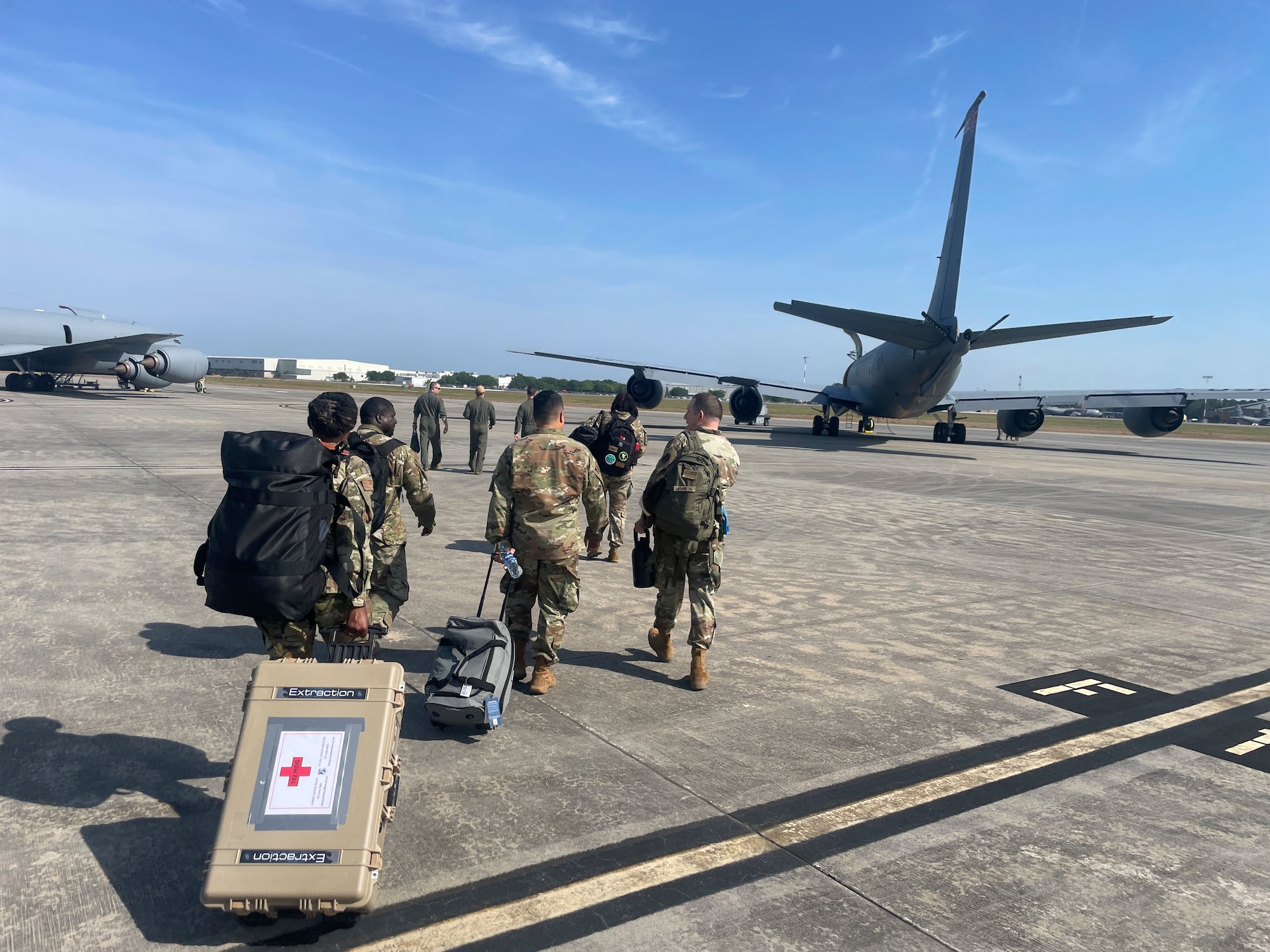 Group of Airmen walk towards a KC-135R Stratotanker with luggage