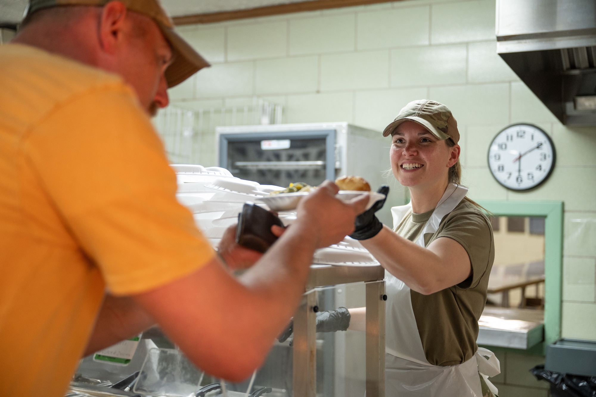 Airman hands a plate of food to another