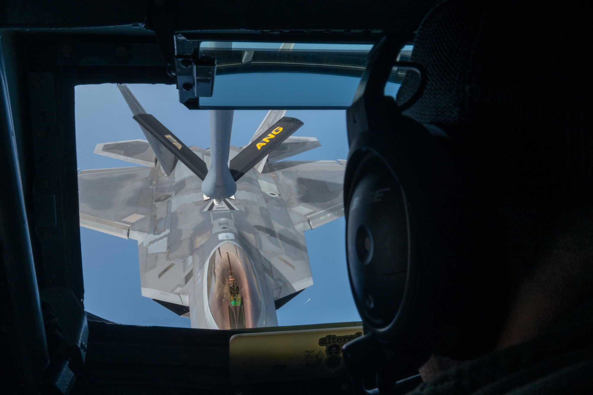 View over the shoulder of boom operator looking at an F-22 being refueled in air