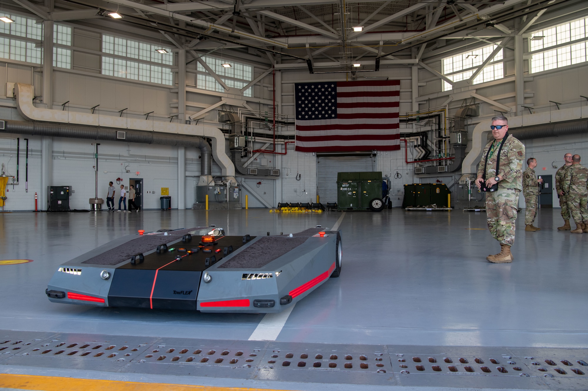 A remotely operated tug is maneuvered out of a hangar by Airmen