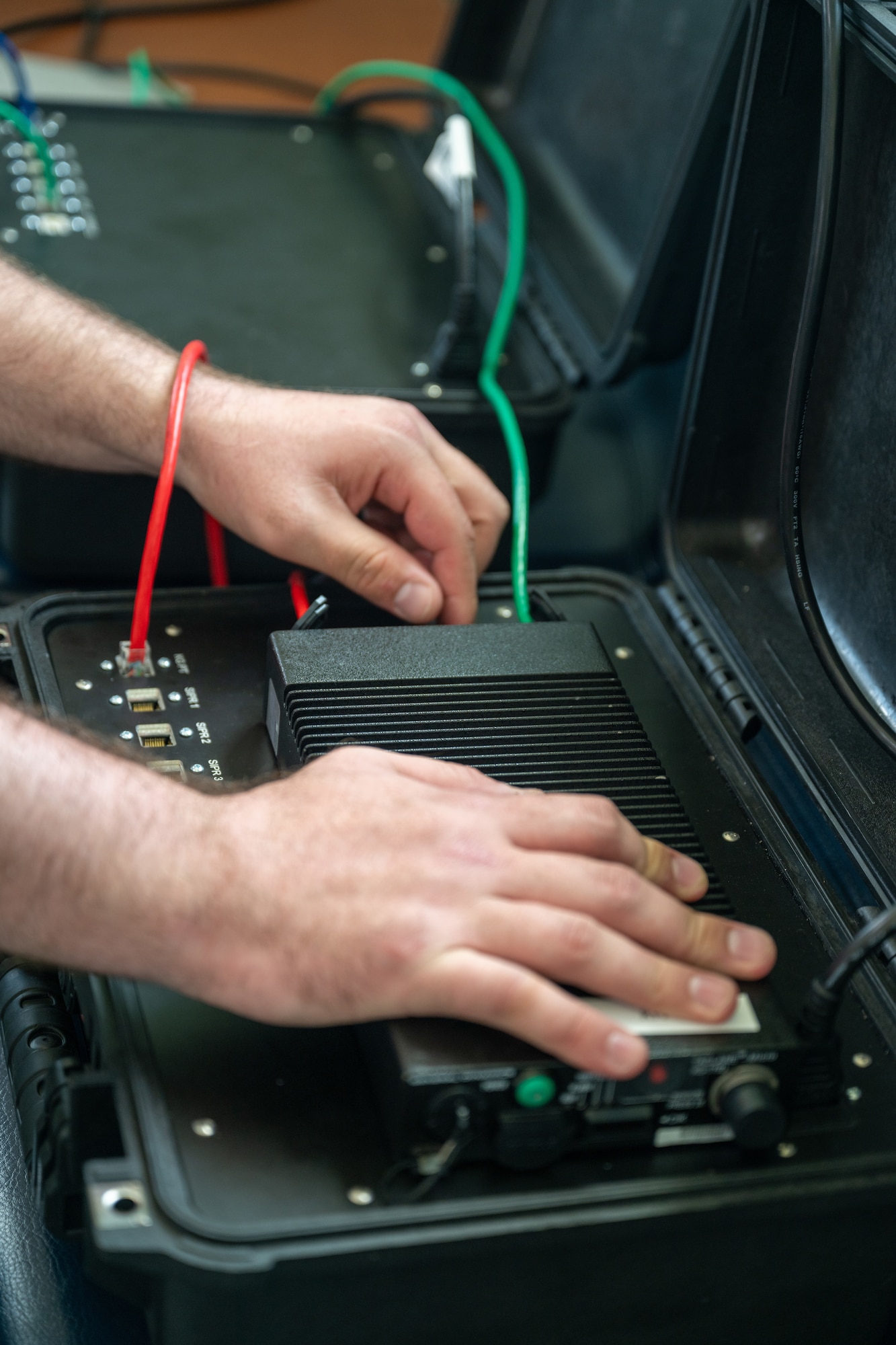 View of communications equipment inside portable cases, Airmen's hands connecting network cords