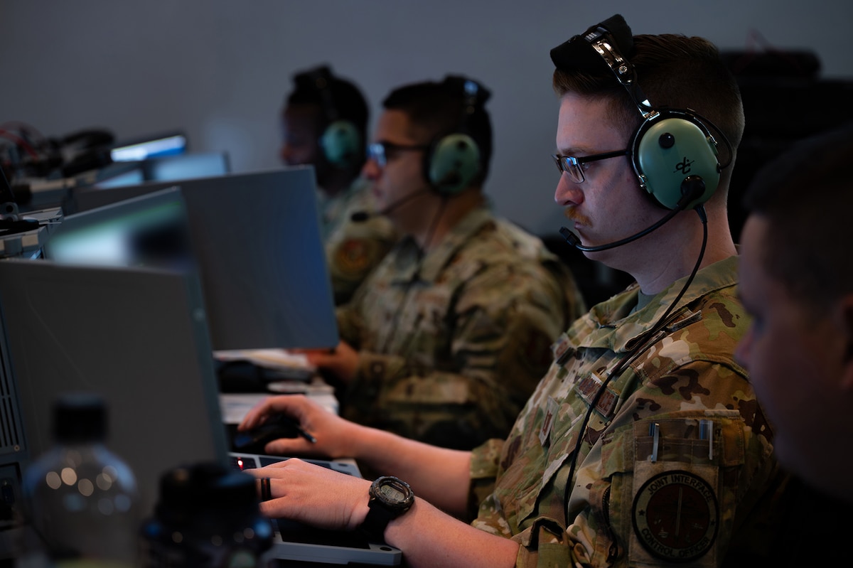 photo of US Airmen wearing headsets working on computers