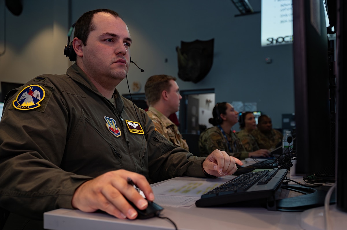photo of US Airmen wearing headsets working on computers