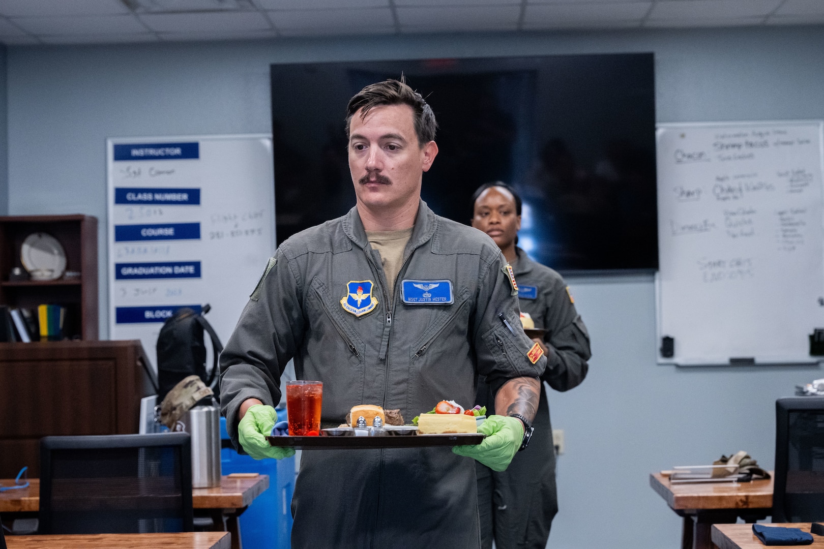 Master Sgt. Justin Hester of the 344th Training Squadron carries a tray while serving lunch for guests as part of the Executive Mission Aviator course