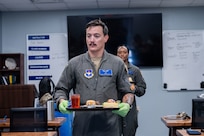 Master Sgt. Justin Hester of the 344th Training Squadron carries a tray while serving lunch for guests as part of the Executive Mission Aviator course