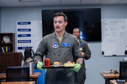 Master Sgt. Justin Hester of the 344th Training Squadron carries a tray while serving lunch for guests as part of the Executive Mission Aviator course
