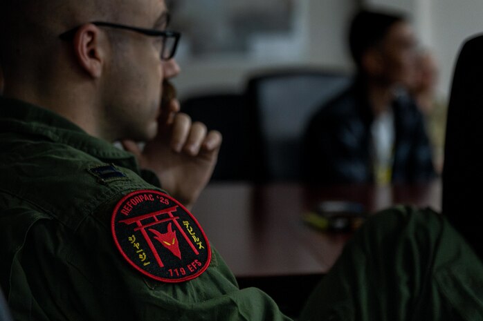 A temporary duty pilot assigned to the 119th Expeditionary Fighter Squadron listens during an exercise Resolute Force Pacific (REFORPAC) 2025 mission brief.