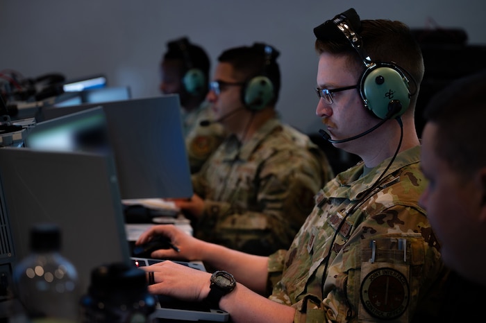 photo of US Airmen wearing headsets working on computers