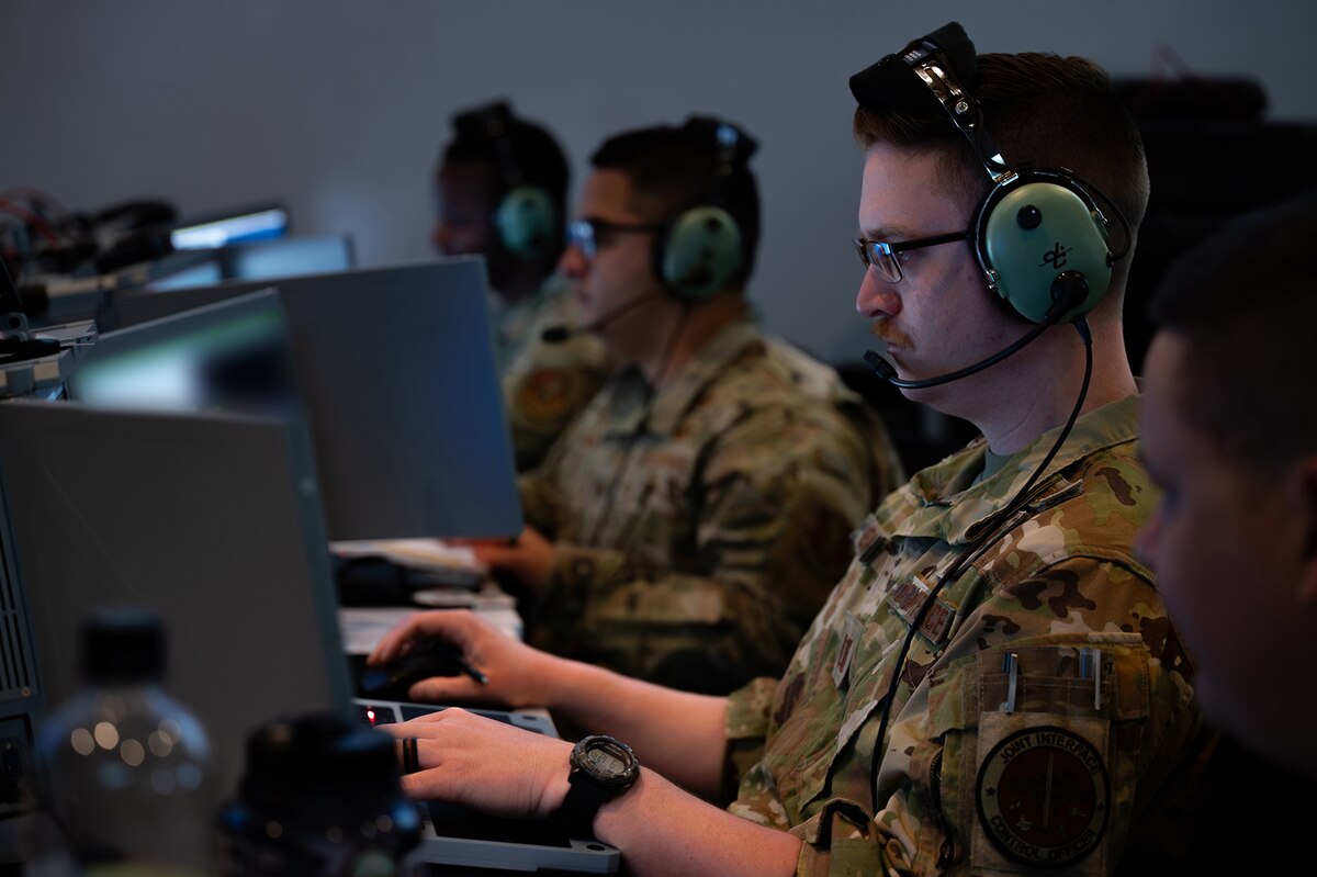 photo of US Airmen wearing headsets working on computers