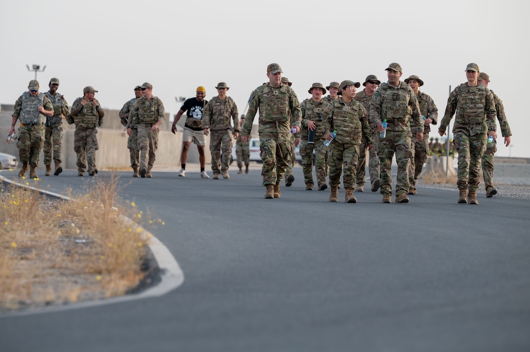 A group of Airmen walk toward the camera along a path during a ruck march