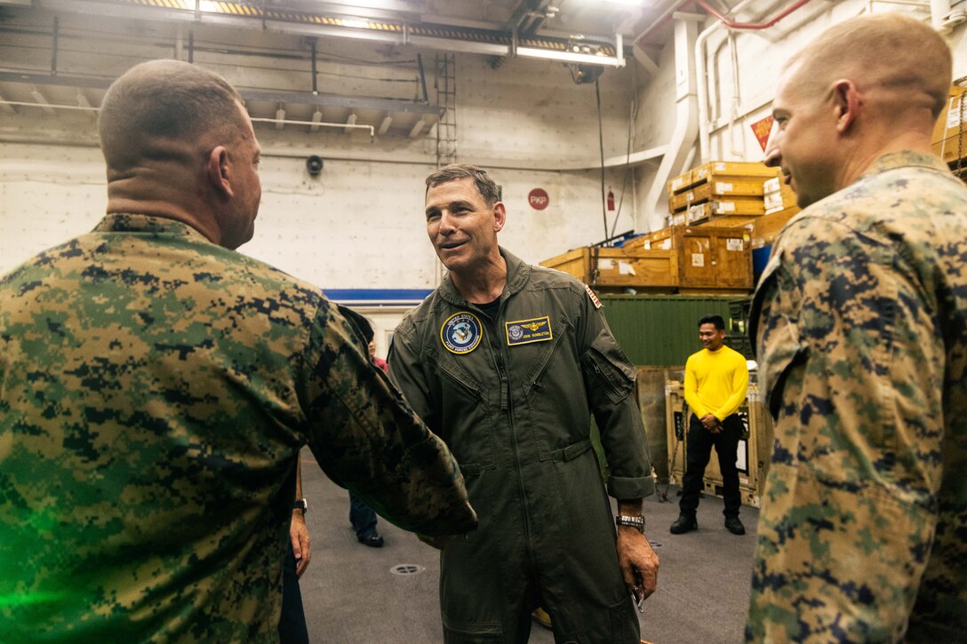 U.S. Navy Vice Adm. John Gumbleton, center, deputy commander of U.S. Fleet Forces Command, and Master Gunnery Sgt. Alex Reyes, operations chief with the Battalion Landing Team 3/6, 22nd Marine Expeditionary Unit (Special Operations Capable), shake hands during his visit aboard the San Antonio-class amphibious transport dock ship USS San Antonio (LPD 17), Iwo Jima Amphibious Ready Group, as part of Composite Training Unit Exercise, while underway in the Atlantic Ocean, June 29, 2025. During COMPTUEX, the IWOARG and 22nd Marine Expeditionary Unit (Special Operations Capable), refine tactics, techniques, and procedures to execute warfighting functions that enhance operational readiness and lethality as a unified IWOARG/22 MEU(SOC) team. (U.S. Marine Corps photo by Cpl. Maurion Moore)