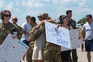 A man hugs a woman holding a sign