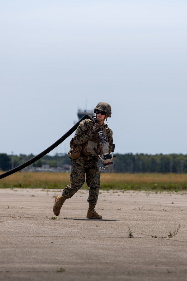 U.S. Marine Corps Cpl. Johnson Anders, an expedient fuel technician with Marine Wing Support Squadron 471, Marine Aircraft Group 41, 4th Marine Aircraft Wing, moves a fuel hose in front of an MV-22B Osprey assigned to Marine Medium Tiltrotor Squadron (VMM) 764, during Atlantic Alliance 2025 at Cape Cod, Massachusetts, July 5, 2025. AA25 is a premier naval integration exercise designed to enhance interoperability among U.S. Navy, Marine Corps and allied forces. (U.S. Marine Corps photo by Sgt. Emely Gonzalez)