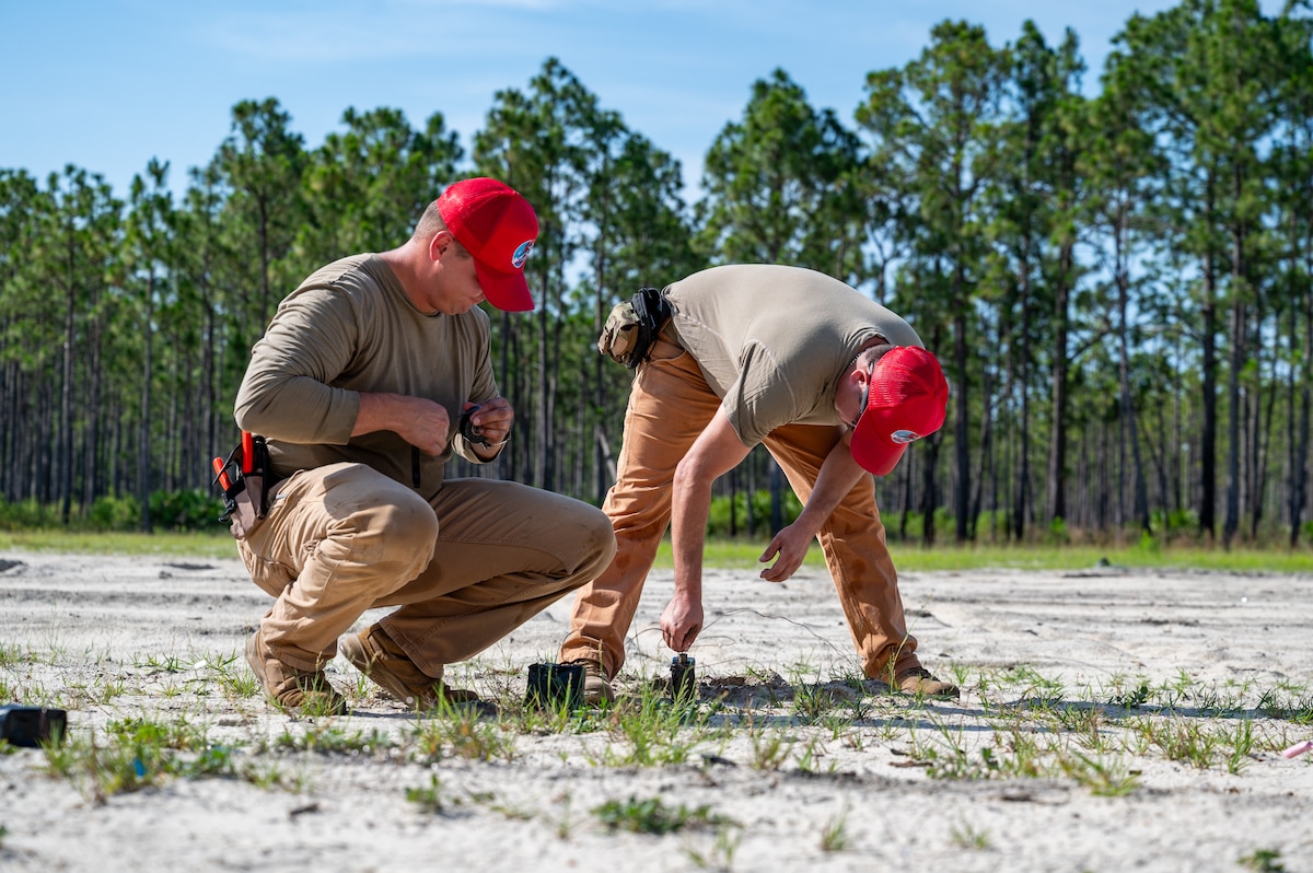 Staff Sgts. Alec Freeman and Cody Hood, 823rd Rapid Engineer Deployable Heavy Operational Repair Squadron Engineers members, prime expolsives with electrical blasting caps at the explosive ordnance disposal range at Hurlburt Field, Fla., June 25, 2025. RED HORSE demolition team members practiced arming and detonating different types of explosives safely. (U.S. Air Force photo by Senior Airman Cesar J. Navarro)