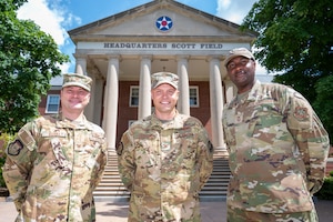Three uniformed Airmen stand together and smile for a photo