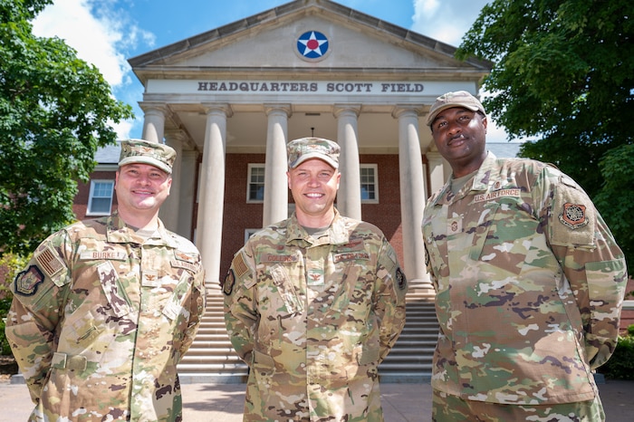 Three uniformed Airmen stand together and smile for a photo