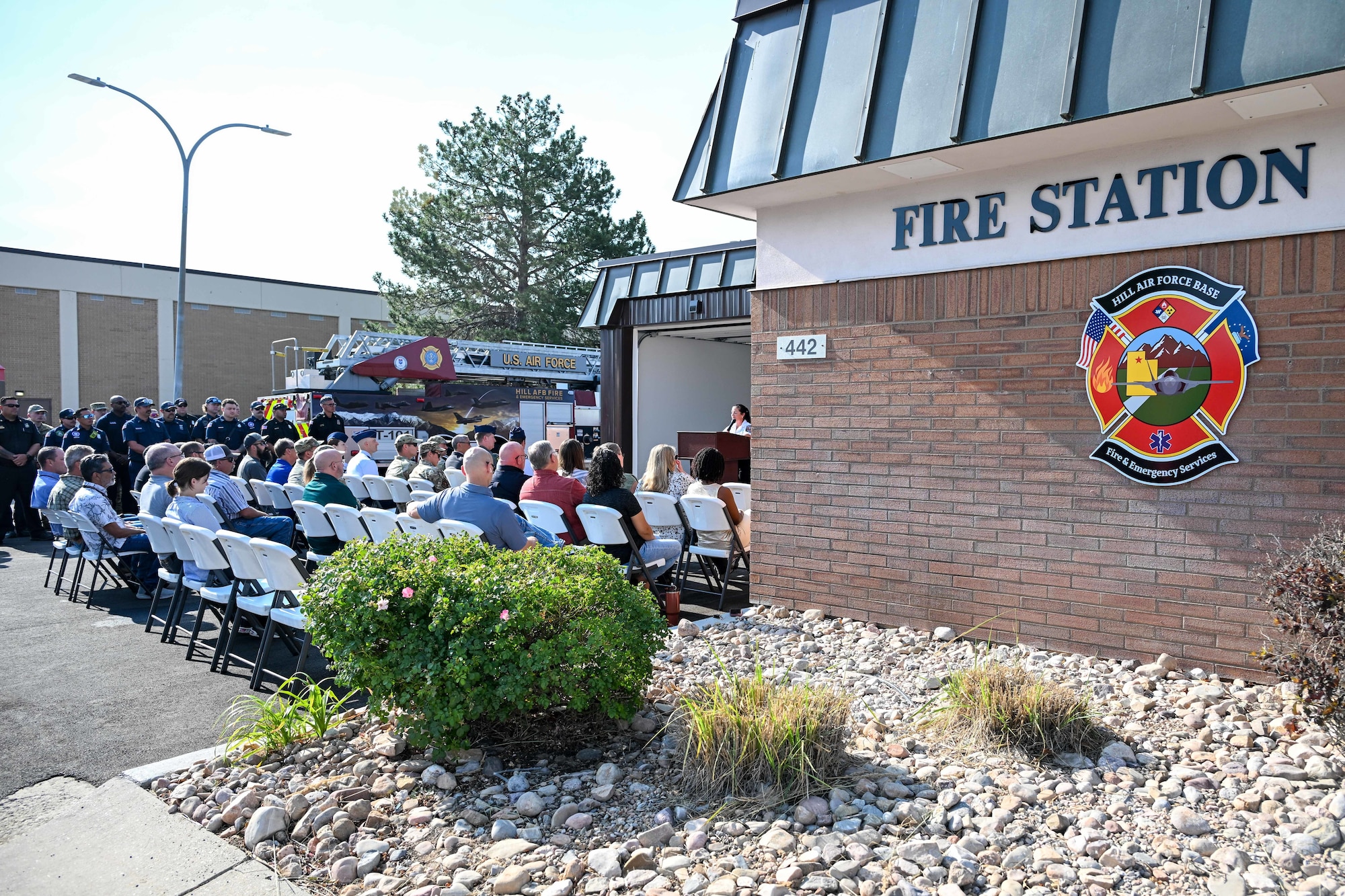 Speaker in front of a fire station speaking to an audience
