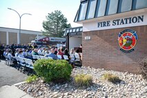 Speaker in front of a fire station speaking to an audience