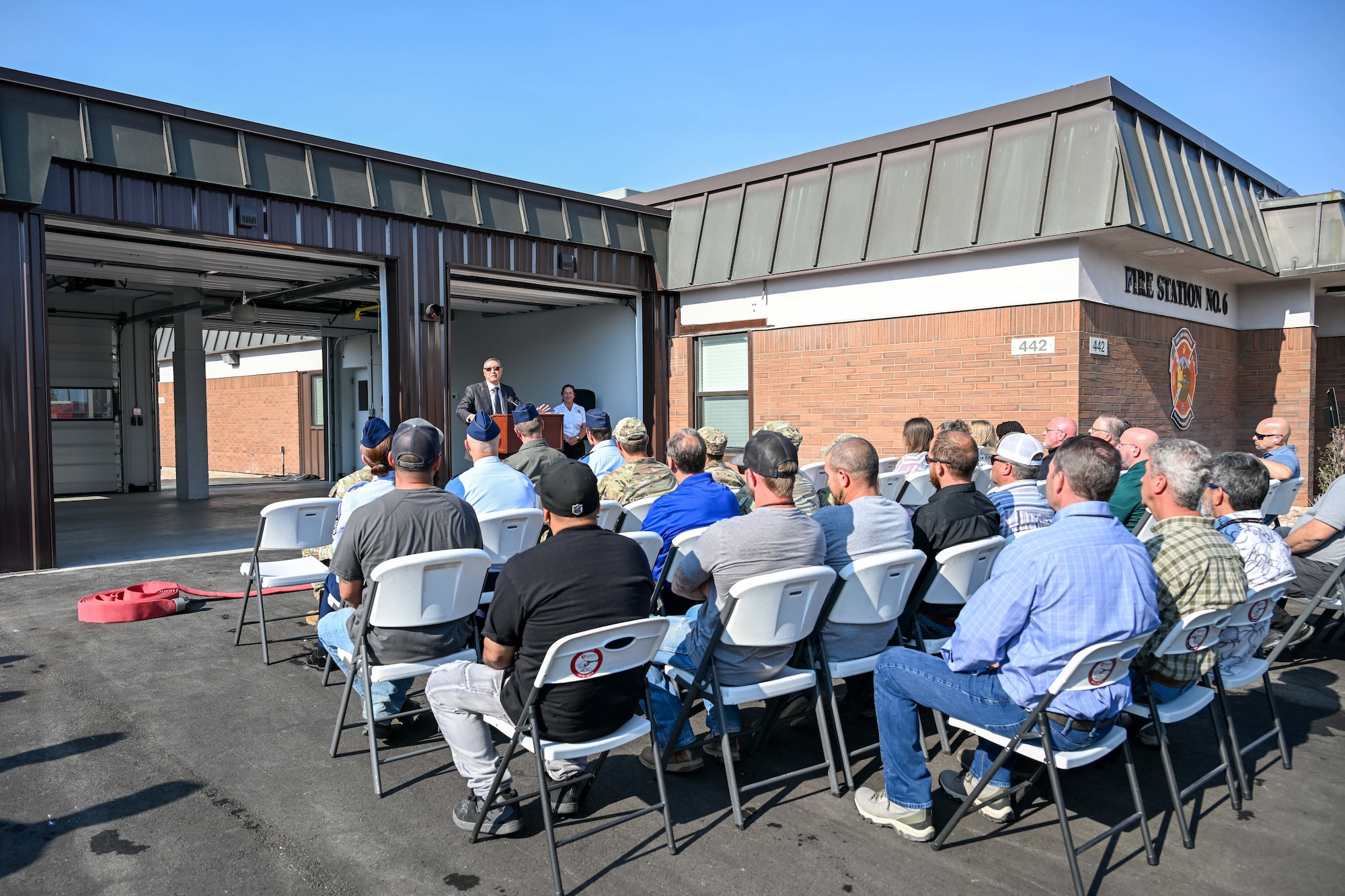 Speaker in front of a fire station speaking to an audience