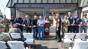 People with an uncoupled fire hose in front of a fire station bay