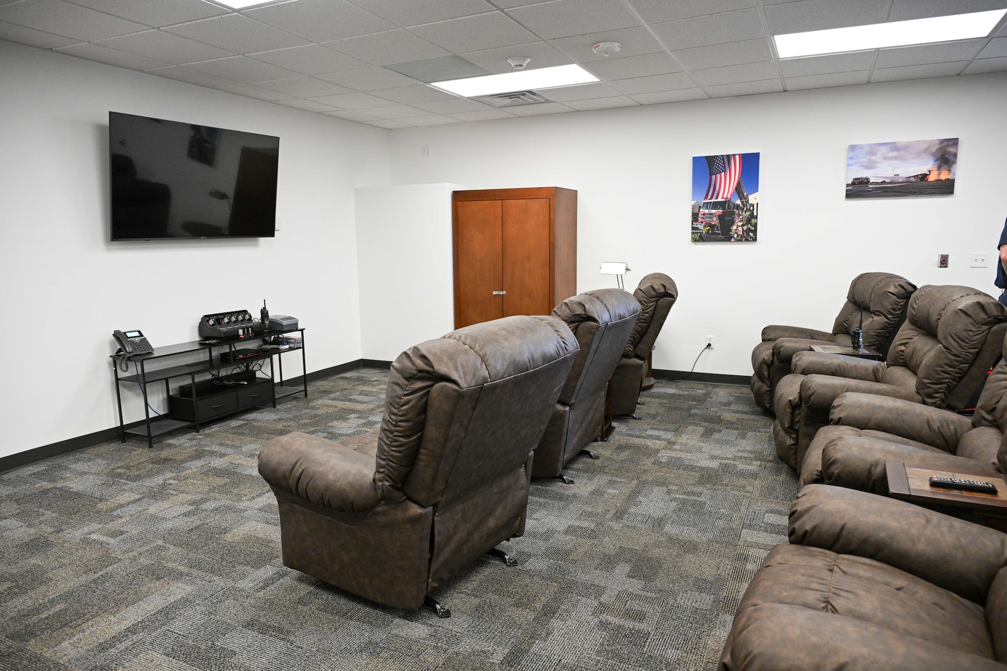 Several recliner chairs lined up in front of a tv