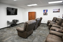 Several recliner chairs lined up in front of a tv