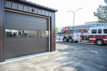 A fire station bay in foreground with a fire engine truck in background