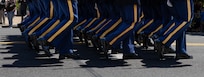 Legs of Army Soldiers who are dressed in ceremonial uniforms and marching in a parade.