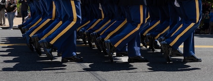 Legs of Army Soldiers who are dressed in ceremonial uniforms and marching in a parade.