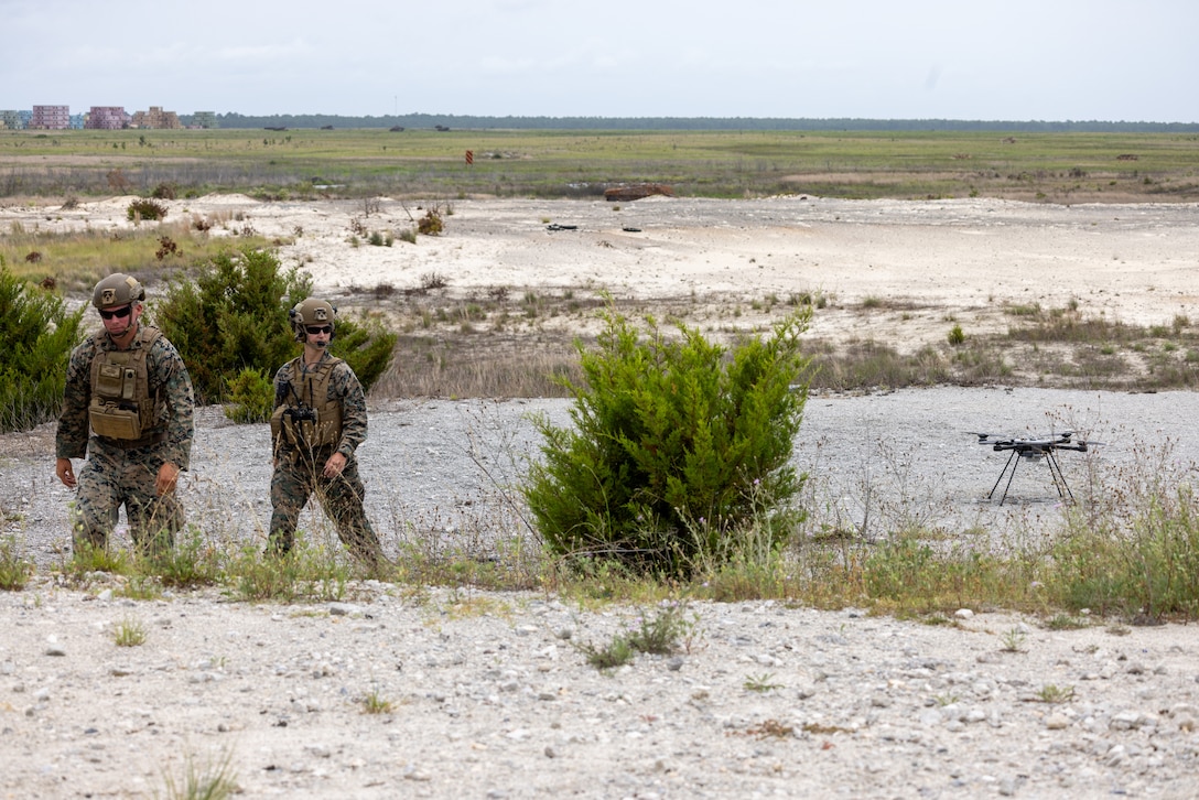 U.S. Marine Corps Staff Sgt. Ronald Johnson II, left, an instructor with Small Unmanned Aircraft Systems School, Advanced Infantry Training Battalion, and a native of South Carolina, and Maj. Jessica Del Castillo, right, the officer in charge of SUASS, AITB, and a native of South Carolina, walk up range after inspecting an R80D SkyRaider small unmanned aircraft system (SUAS) in preparation for a combined arms live-fire training exercise involving the employment of small unmanned aircraft systems (SUAS) to deliver munitions on designated targets at Camp Lejeune, North Carolina, July 2, 2025. This event marked the first time munitions were employed from SUAS during a live-fire training exercise on Camp Lejeune, demonstrating the capability of integrating aerial strike capabilities at the tactical level. (U.S. Marine Corps photo by Cpl. Zachariah Ferraro)