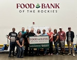 A group of people stand behind a sign of a non-profit they volunteered at.