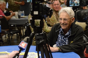 Robert Irwin sits and smiles while being interviewed by journalists with a microphone and two cameras