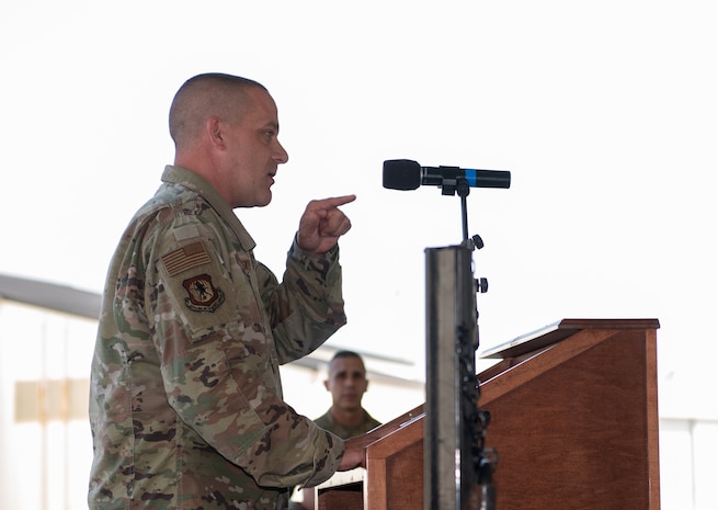 U.S. Air Force Colonel gives stands behind podium and gives speech to unit.