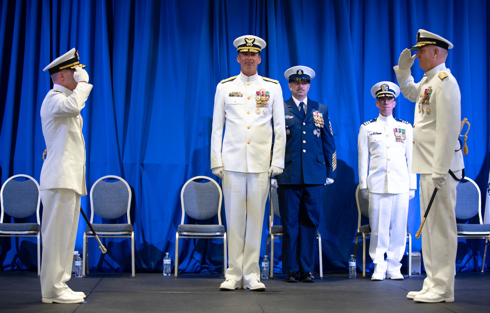 Coast Guard officers salute during a change of command ceremony