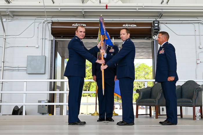 U.S. Air Force Reserve Col. Matthew Barry, 919th Special Operations Group commander, passes the guidon to Lt. Col. Jason Fox, incoming 711th Special Operations Squadron commander, during a change of command ceremony at Hurlburt Field, Florida, July 11, 2025. In addition to the change of command, the event marked the squadron’s transition to an operational AC-130J Ghostrider gunship mission.  (U.S. Air Force photo by Liz Easterling)